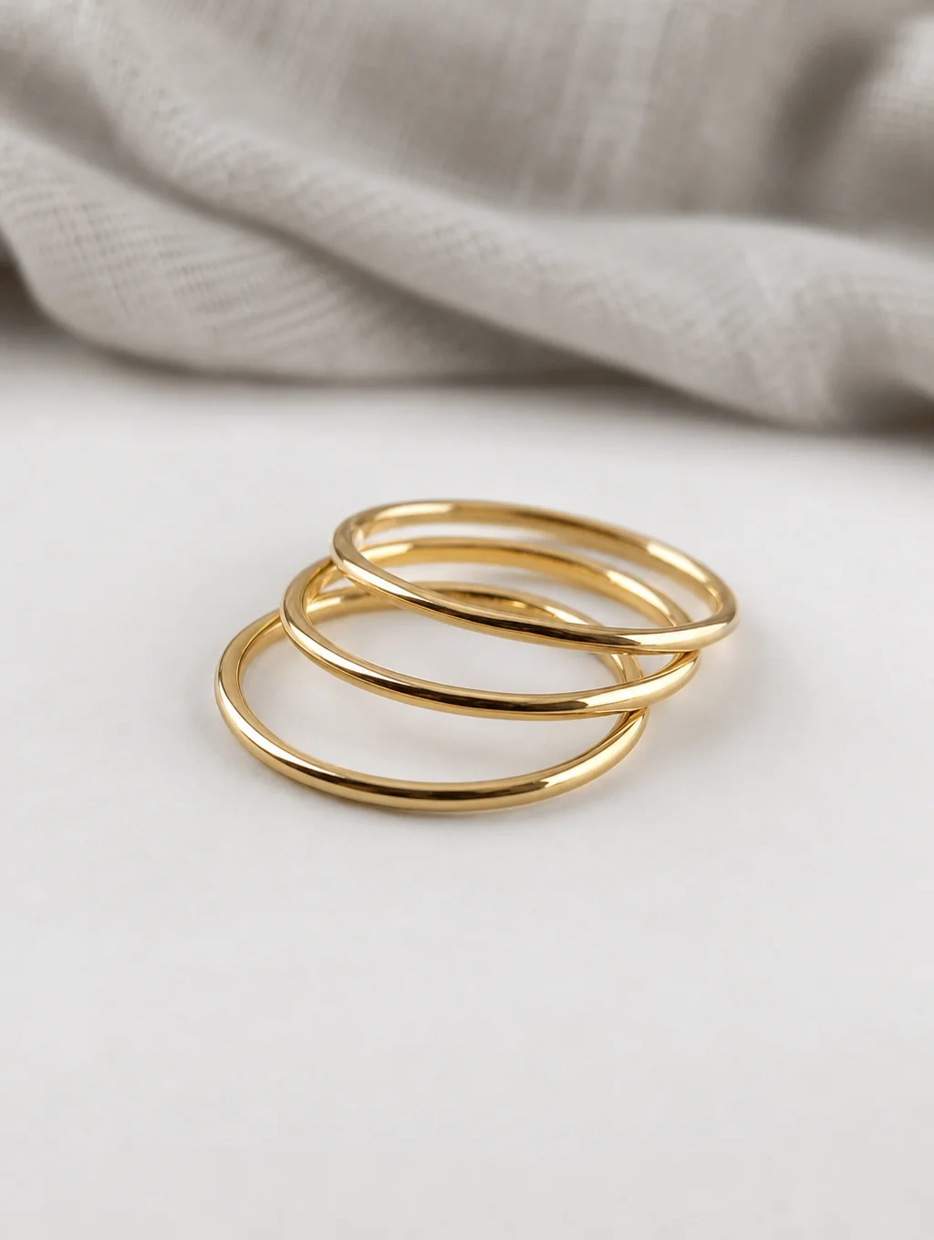 Stacking gold rings and diamond bands on a travertine stone surface